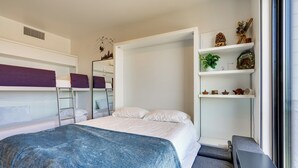 Quarto de hotel moderno com beliches, uma escrivaninha e uma janela com vista.