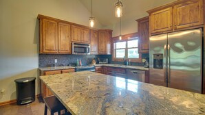 A kitchen with wooden cabinets, a granite countertop, stainless steel appliances, and pendant lighting.
