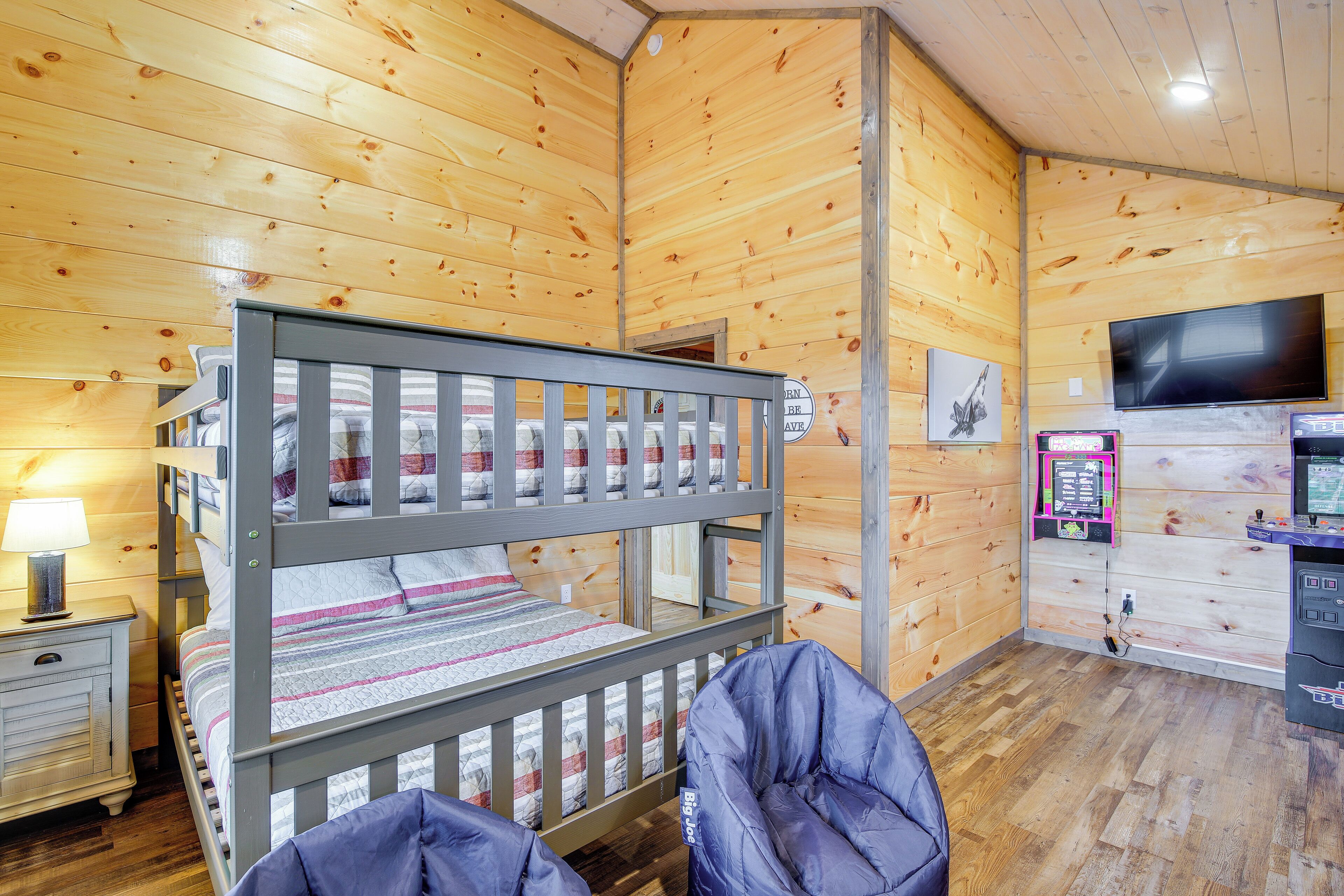 A bunk bed with a wooden headboard, a bedside table with a lamp, a flat-screen TV, and a vending machine.