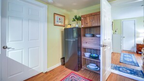 Una cocina con refrigerador, armarios de madera y una planta pequeña encima.