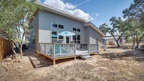 A two-story house with a covered patio, a fenced deck, and a sandy backyard. - Modern Canyon Lake Vacation Home w/ Furnished Deck (Canyon Lake)