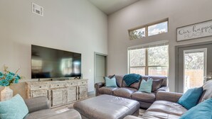 A living room with a large flat-screen TV, two brown leather sofas, and a matching ottoman. - Modern Canyon Lake Vacation Home w/ Furnished Deck (Canyon Lake)