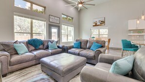 A spacious living room with leather sofas, a large ottoman, and a ceiling fan. - Modern Canyon Lake Vacation Home w/ Furnished Deck (Canyon Lake)