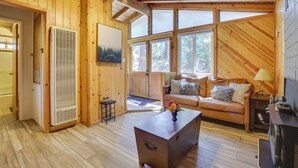 A cozy cabin interior with a wooden interior, a sofa, a coffee table, and a fireplace. - Pet-friendly Big Bear Cabin, Near Hiking & Skiing! (Big Bear City)