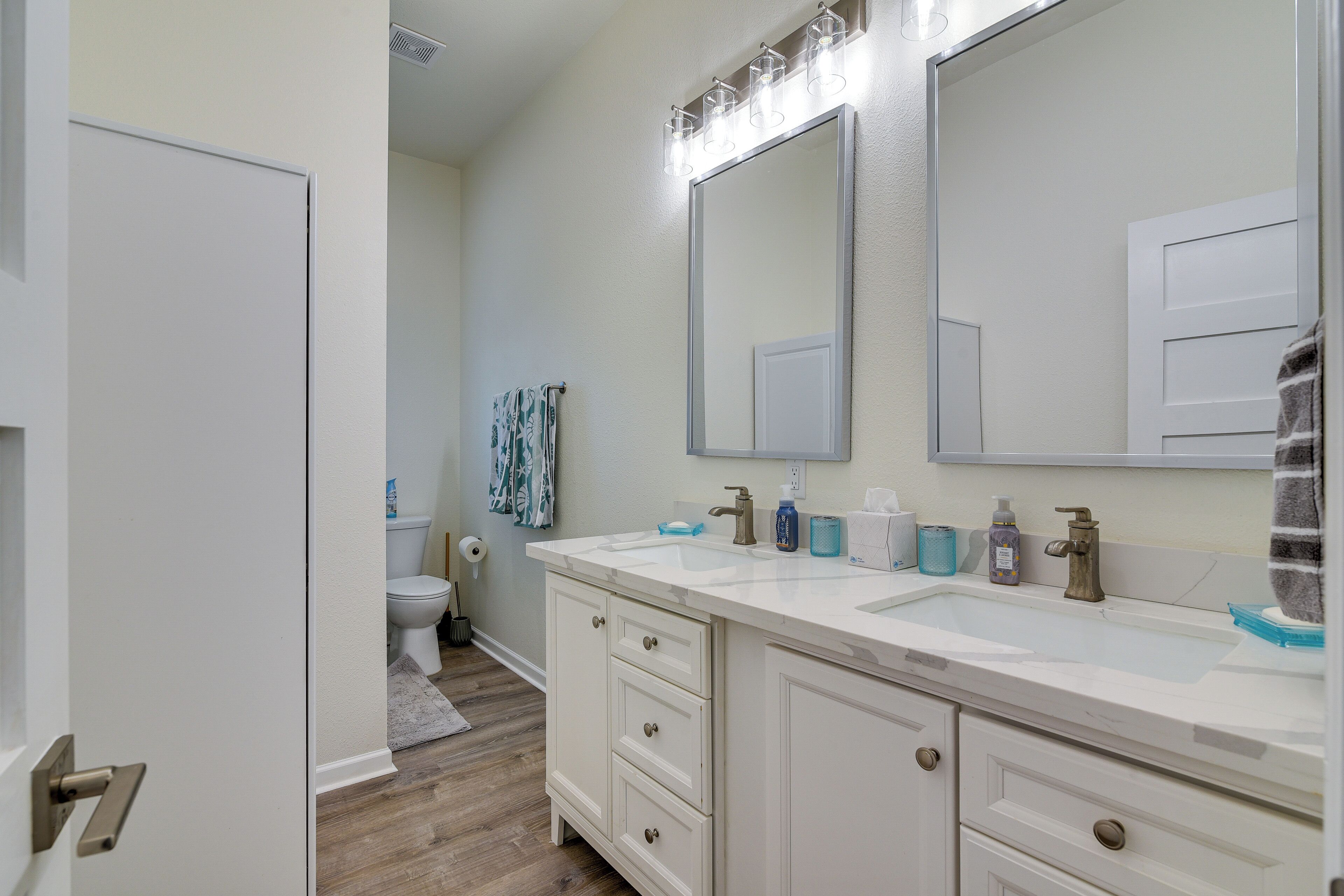 Une salle de bain avec un meuble-lavabo blanc, un double vasque et un grand miroir.
