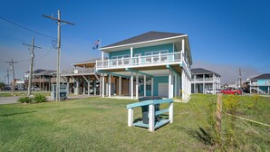 Een twee verdiepingen tellend strandhuis met een balkon, een klein zitgedeelte buiten en een vlag op het dak.