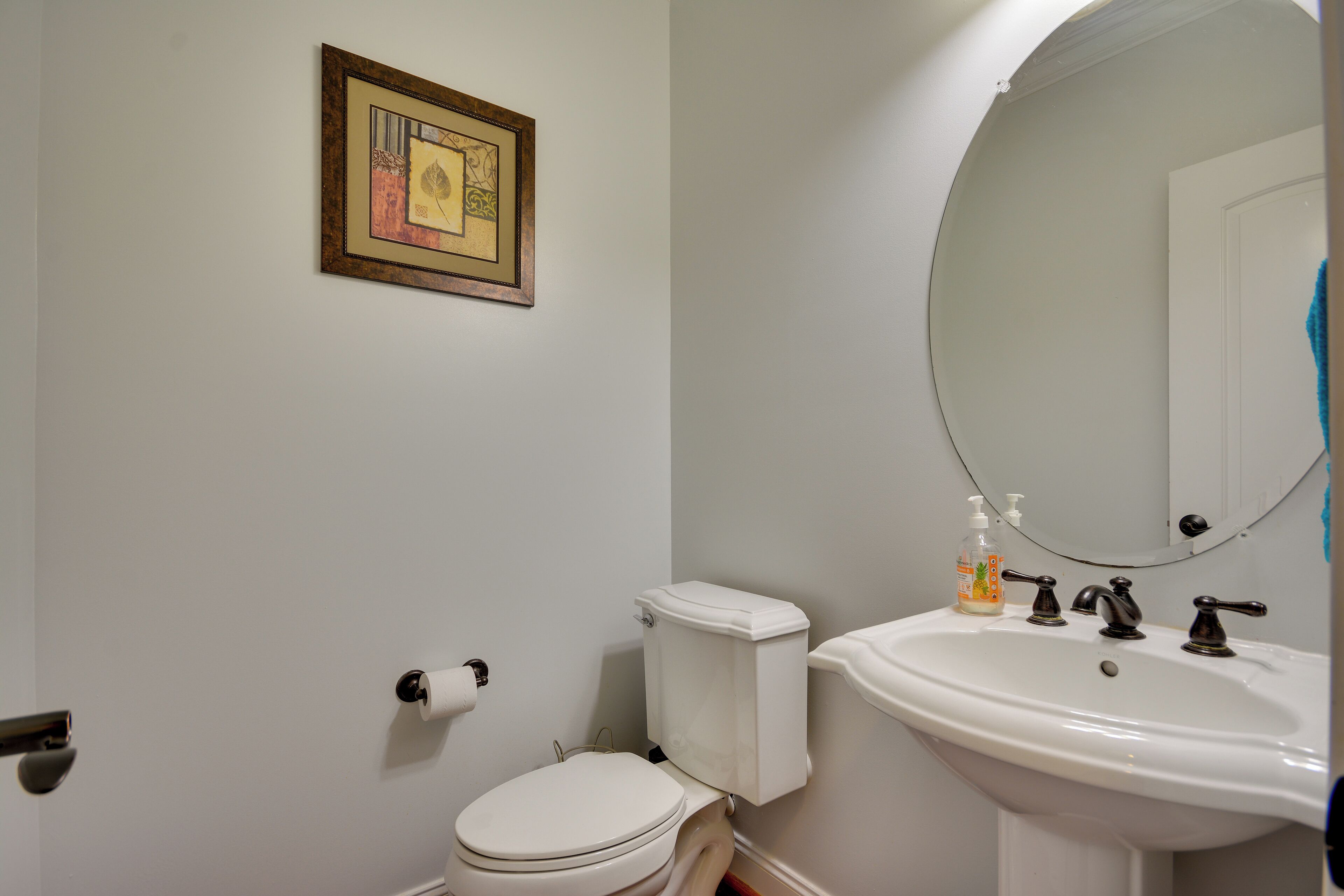 A bathroom with a toilet, sink, and mirror.