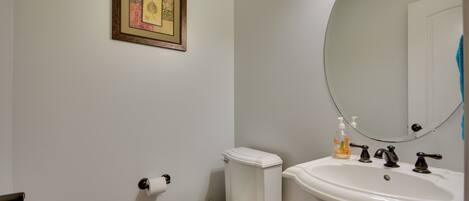 A bathroom with a toilet, sink, and mirror.