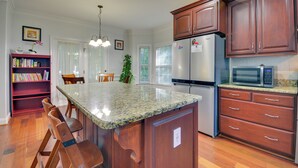 A kitchen with wooden cabinets, a granite countertop, a refrigerator, and a microwave. - High Point Vacation Rental w/ Private Deck! (High Point)