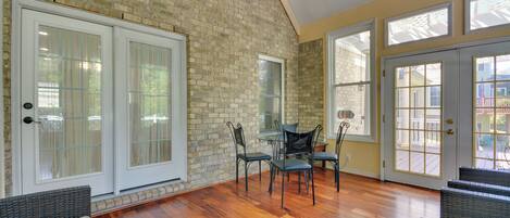 A spacious room with a brick wall, large windows, and a wooden floor.