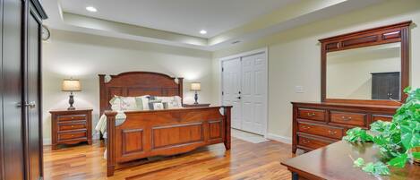 A bedroom with a wooden bed, nightstands, a dresser, and a large mirror.