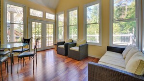 A spacious room with a wooden floor, large windows, a dining table with chairs, and a sofa. - High Point Vacation Rental w/ Private Deck! (High Point)