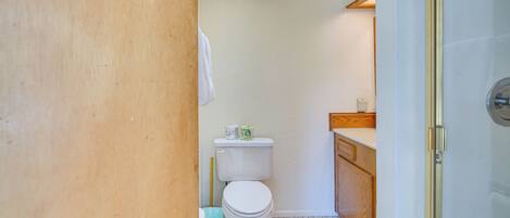 Un baño pequeño con un inodoro, un cubo de basura y un armario de madera.