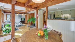 A spacious living area with wooden beams, a dining table with fruit and flowers, and a kitchen in the background. - Ellsworth Home ~ 18 Mi to Acadia Nat'l Park! (Ellsworth)