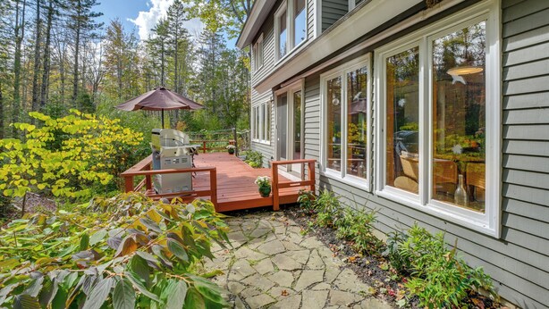 A house with a deck, a patio, and a view of the surrounding forest. - Ellsworth Home ~ 18 Mi to Acadia Nat'l Park! (Ellsworth)