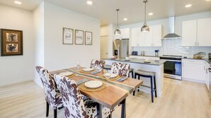 A modern kitchen with white cabinets, stainless steel appliances, and pendant lighting. - Modern Livingston Condo Near Yellowstone River! (Livingston)