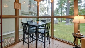 A conservatory with a dining table and chairs, large windows, and string lights. - Gilford Townhome w/ Lakefront Beach & Pool Access! (Gilford)