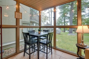 A conservatory with a dining table and chairs, large windows, and string lights.