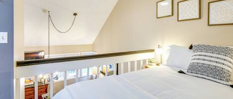 A bedroom with a bed, a ceiling fan, and three framed pictures on the wall.