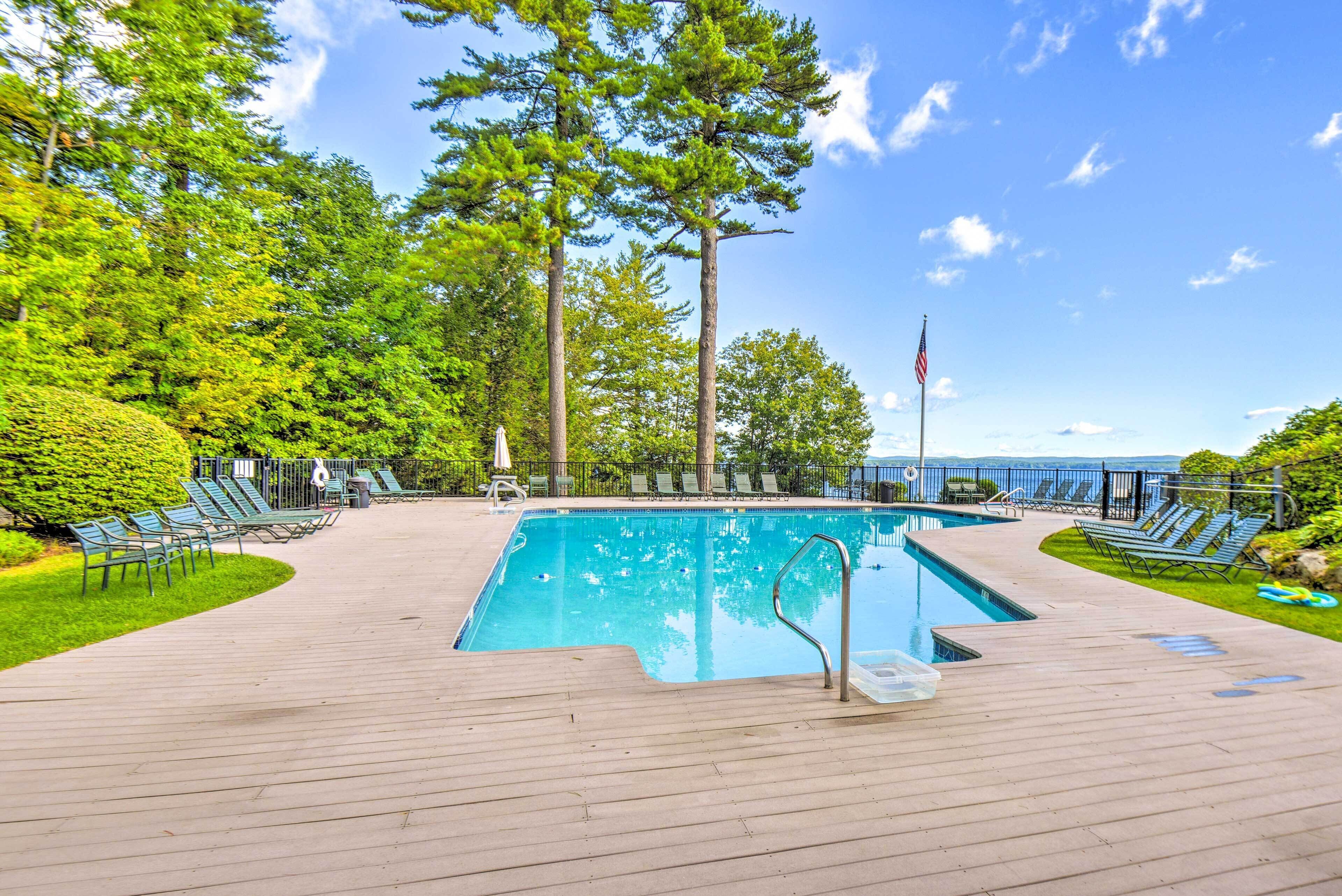 A swimming pool with a wooden deck, lounge chairs, and a flag.