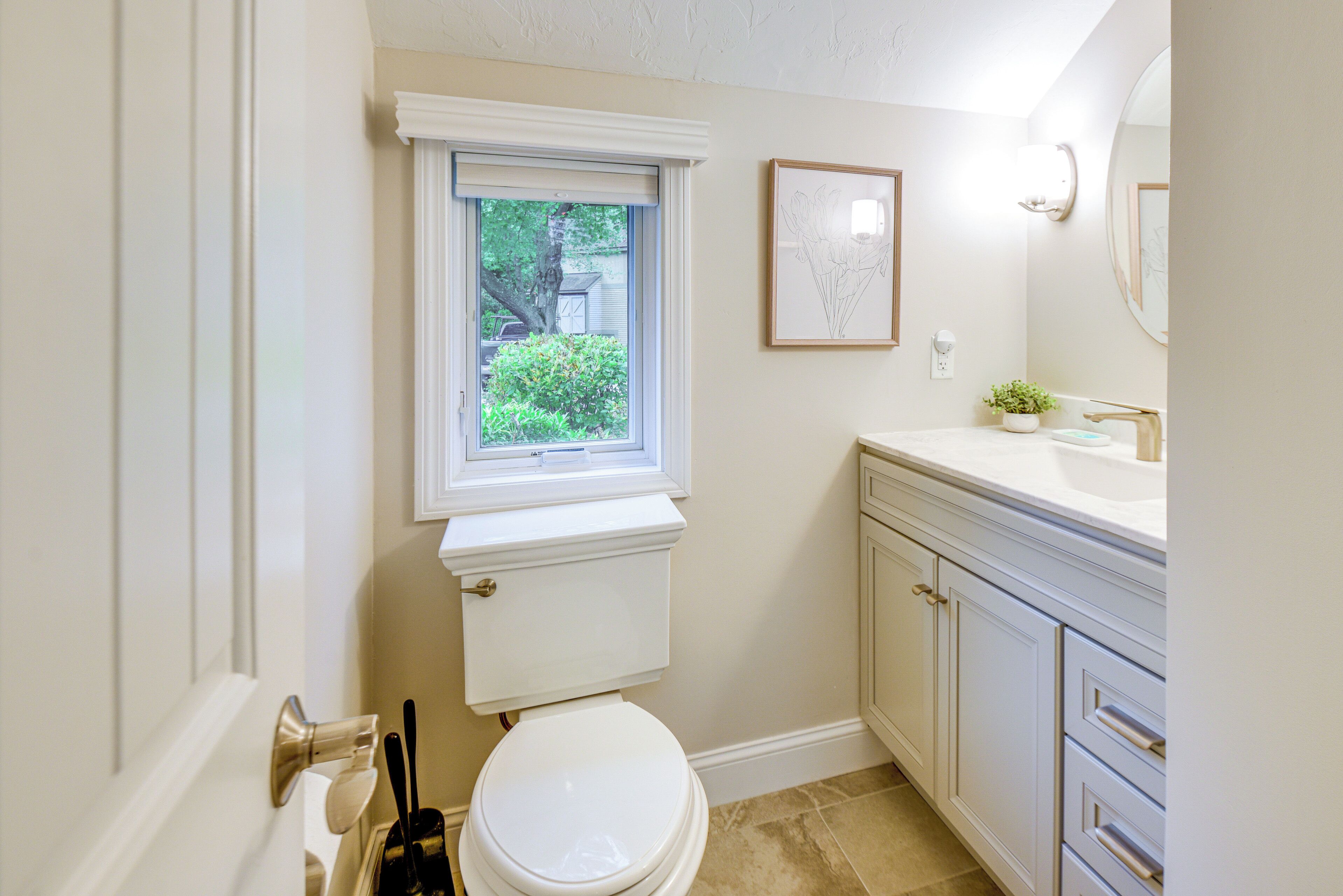 Une salle de bain comprenant des toilettes, une fenêtre, un lavabo et un meuble de rangement.