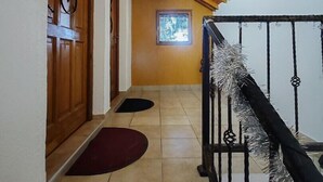 A staircase with a wooden ceiling and a metal railing, leading to a room with a window and a door.