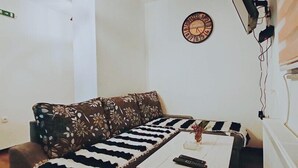 A modern living room with a sectional sofa, a coffee table, a wall clock, and a mounted television.