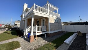 Una casa de dos plantas con balcón, porche delantero y entrada para coches.