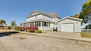 A two-story house with a garage, a covered porch, and a stop sign in the foreground. - Dom Rodzinny Lakeview Getaway - Walk to Lake Huron (Rogers City)