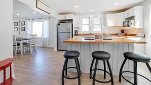A modern kitchen with a wooden countertop, stainless steel appliances, and bar stools. - Dom Rodzinny Lakeview Getaway - Walk to Lake Huron (Rogers City)