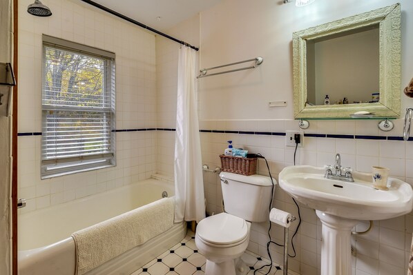 Bathroom features a bathtub, toilet, and sink, with a window and mirror.