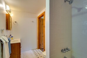 Bathroom features a shower with handheld showerhead, sink, and mirror, plus ample storage for towels.
