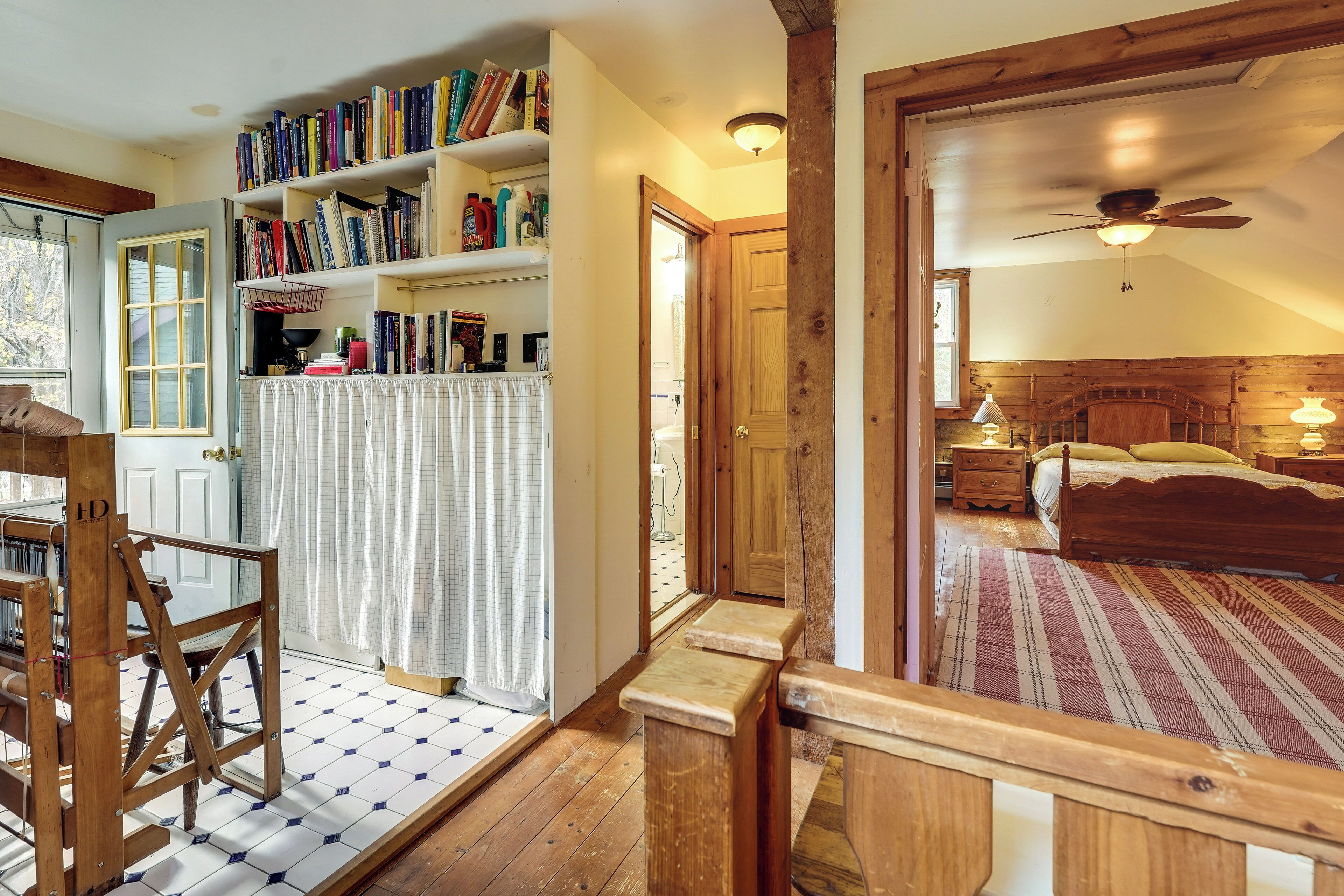 Une chambre à coucher avec une tête de lit en bois, un lit, une table de chevet, une lampe et une bibliothèque remplie de livres.