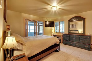 A bedroom with a bed, bedside lamp, dresser, and a TV mounted on the wall. - Pelican Lake House w/ Boat Dock and Sauna! (Pelican Lake)