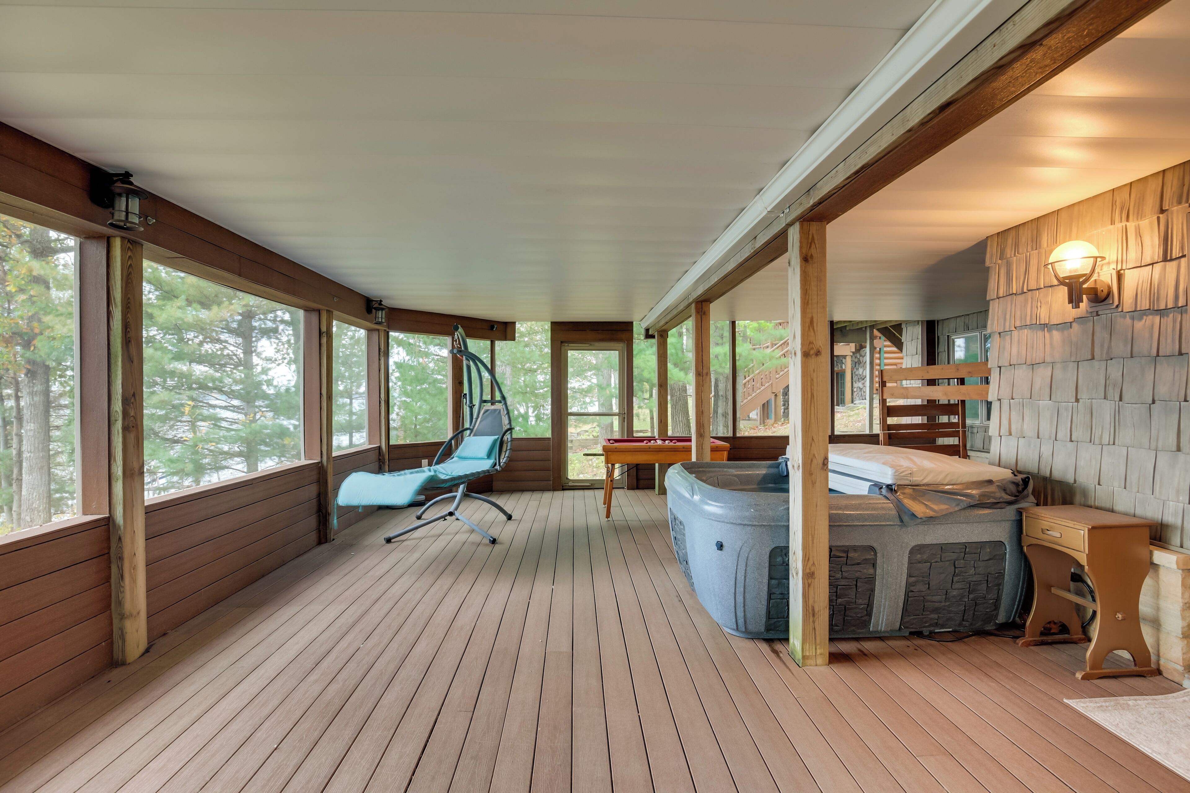 A wooden deck with a hot tub, a chair, and a table.
