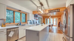 Una cocina moderna con una isla central, electrodomésticos de acero inoxidable y ventanas amplias.