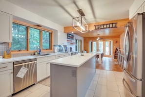 A modern kitchen with white cabinetry, stainless steel appliances, and large windows. - Pelican Lake House w/ Boat Dock and Sauna! (Pelican Lake)