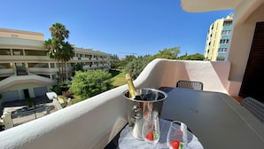 A balcony with a table set for two, featuring a bottle of champagne and two glasses with strawberries. - Vilamoura Twins 2 With Pool by Homing (Loulé)