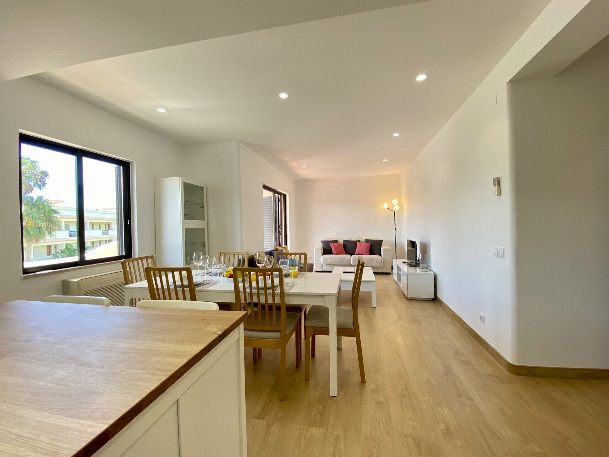 A modern living space with a dining area, a sofa, and a TV.