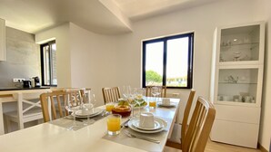 A dining area with a long table set for breakfast, including plates, glasses, and a fruit basket. - Vilamoura Twins 2 With Pool by Homing (Loulé)