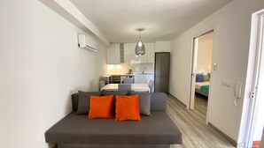 A modern apartment with a grey sofa, orange cushions, a kitchen with white cabinets, and a dining area. - Albufeira Harmony With Pool by Homing (Albufeira)