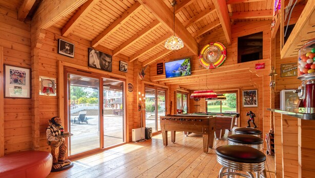 A wooden interior with a pool table, stools, and a billiards table.