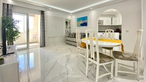 A modern living room with a dining area, a kitchen, and a balcony.