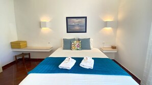 Een hotelkamer met een groot bed, twee nachtkastjes, een stoel en een schilderij aan de muur.