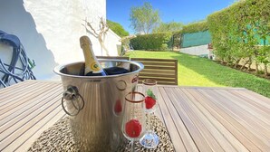 Een metalen emmer met een champagnefles op een houten tafel, buiten.