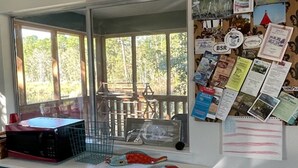 A room with a large window, a bulletin board with various papers, a microwave, and a small fish decoration on the counter. - Peaceful location! Close to everything! Bring the family and dogs! Snowbirds! (Bon Secour)