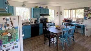 A kitchen with blue cabinets, a dining table with chairs, and a refrigerator with magnets. - Peaceful location! Close to everything! Bring the family and dogs! Snowbirds! (Bon Secour)