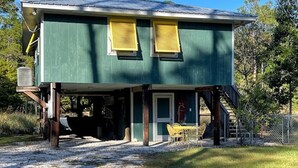 A green building with two windows, a covered porch, and a staircase leading to the entrance. - Peaceful location! Close to everything! Bring the family and dogs! Snowbirds! (Bon Secour)
