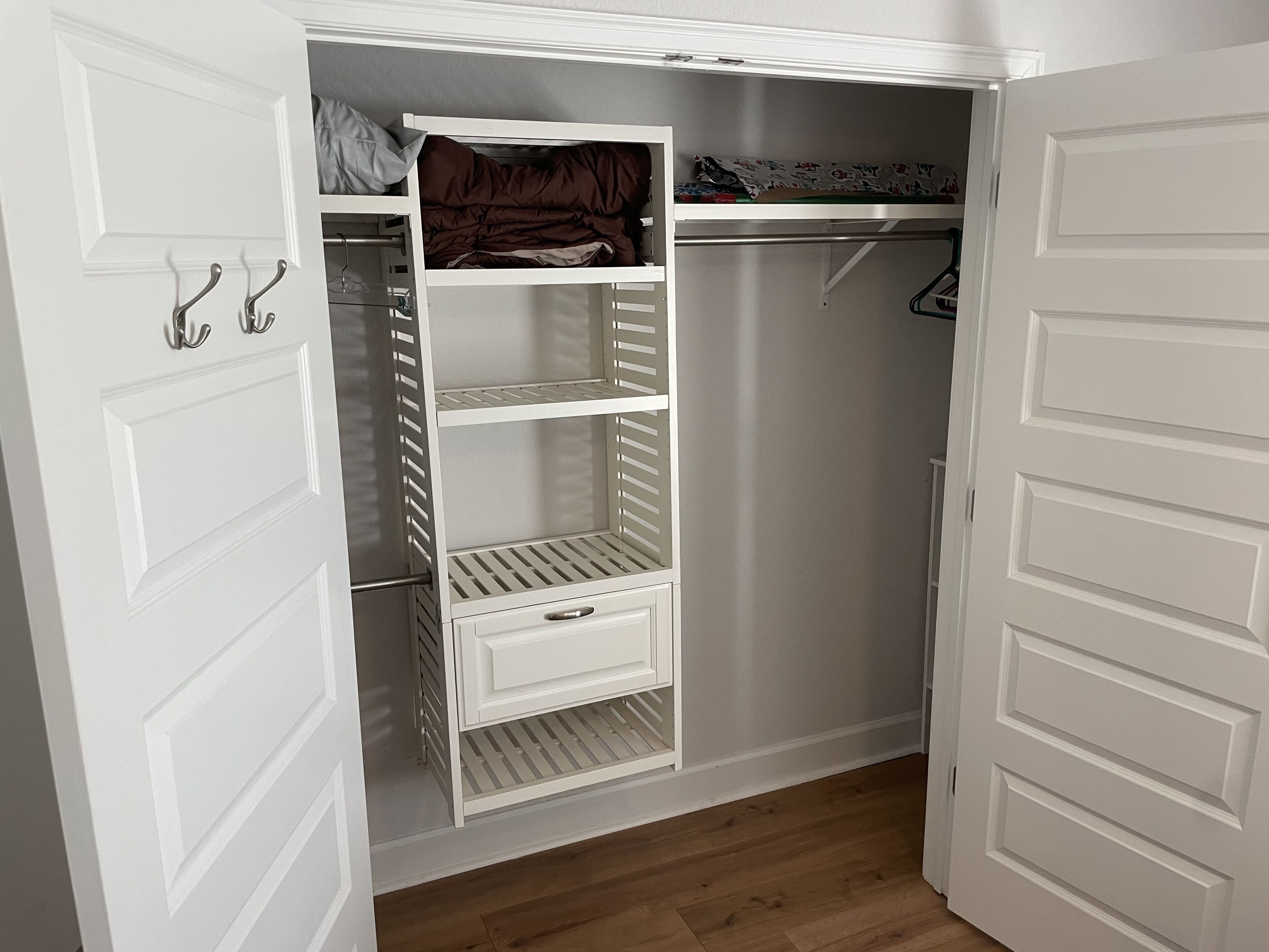 Un armario vestidor con puertas blancas, estanterías y una barra para colgar ropa.