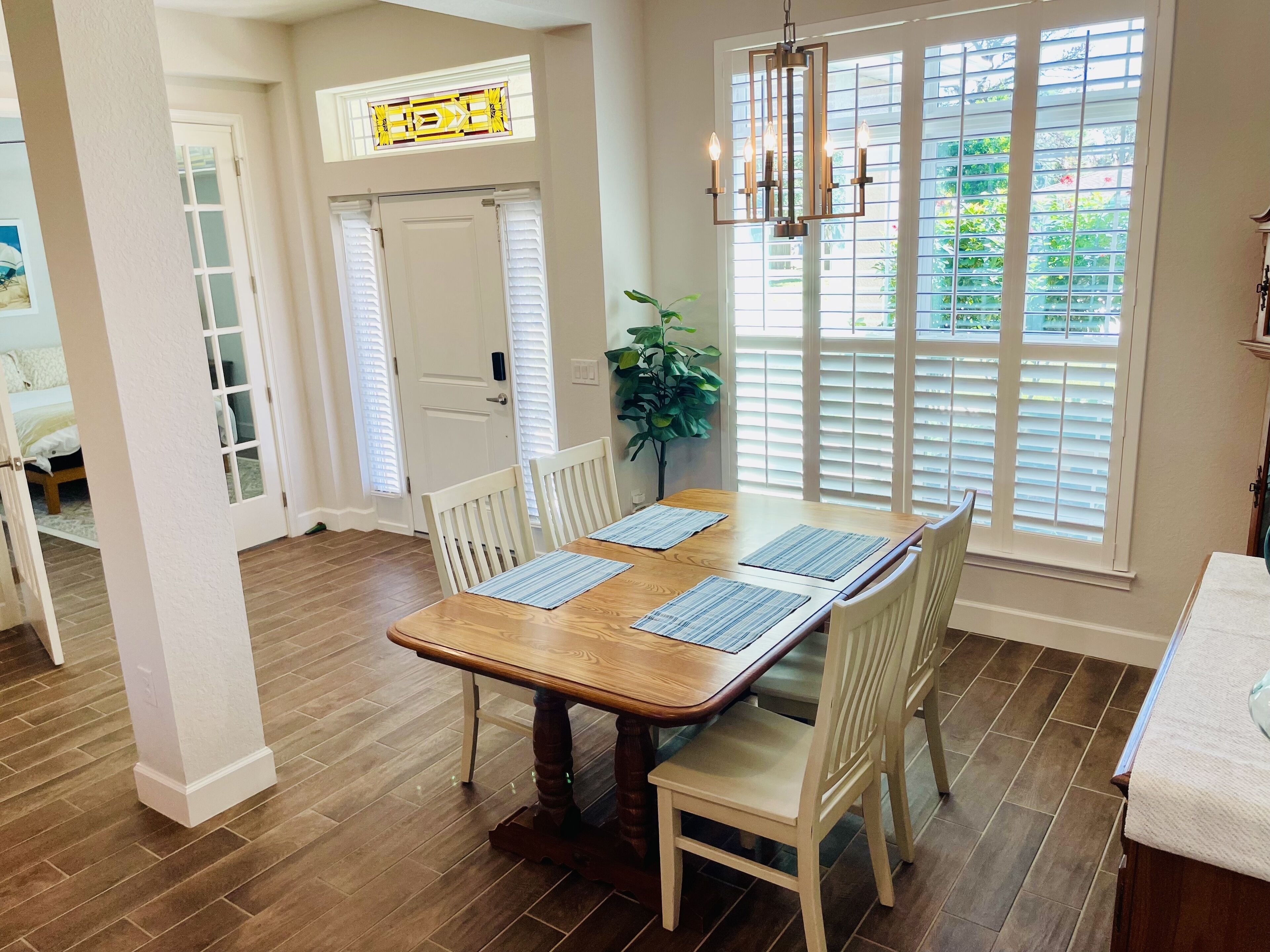 A dining area with a wooden table, white chairs, and a hanging light fixture.
